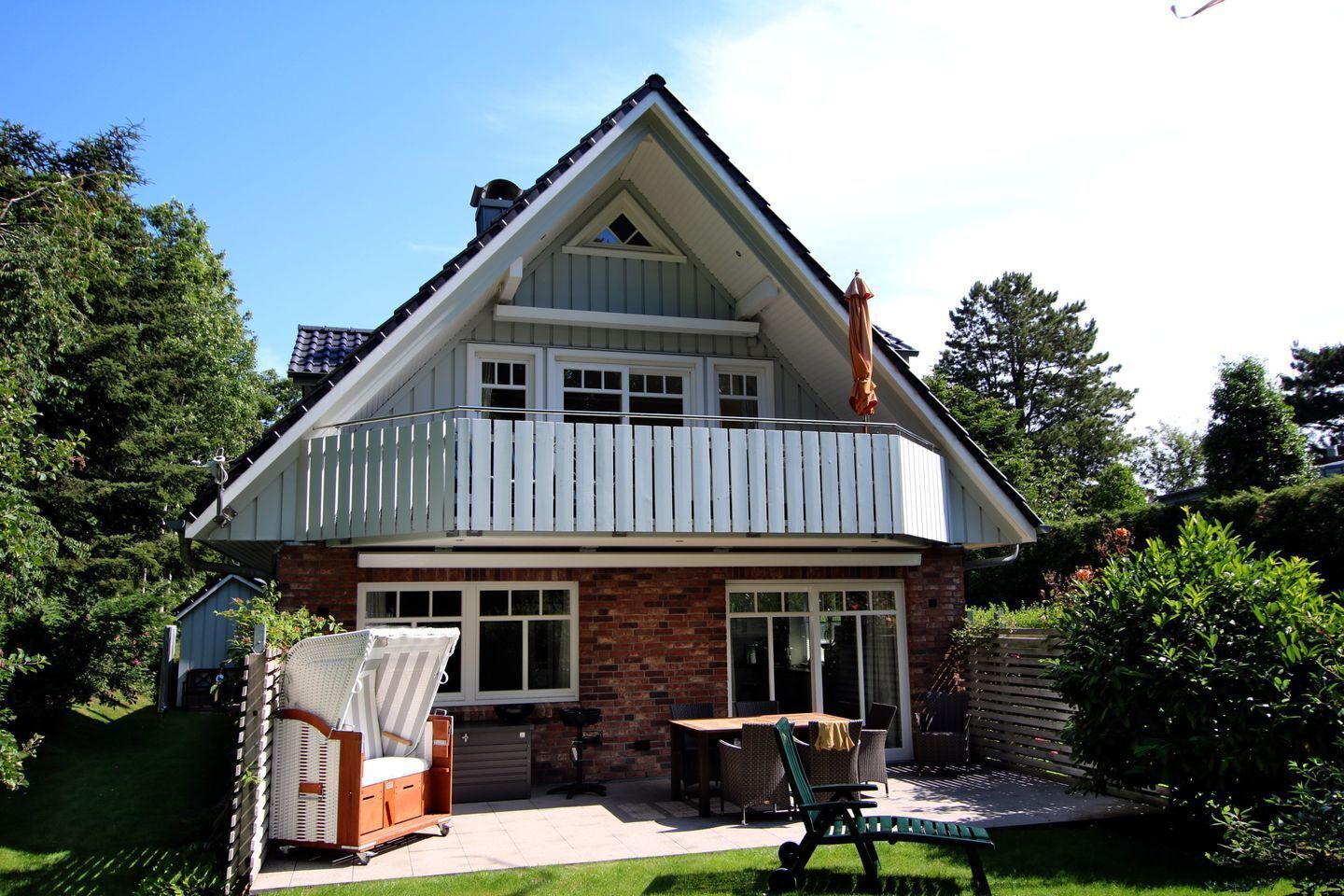 A two-story house with a balcony, a patio with outdoor furniture, and a shed in the backyard.