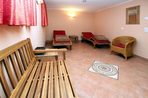 Une pièce avec un banc en bois, deux fauteuils confortables, une petite table et un sol à motifs.
