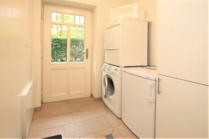 A laundry room with a washing machine, dryer, and stacked laundry baskets.