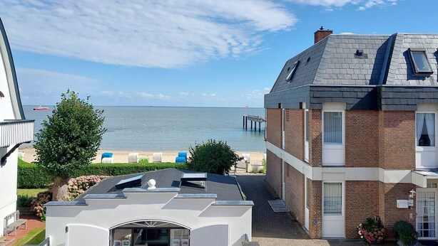 Een landgoed aan de kust met uitzicht op zee, een strand met ligbedden en een pier.