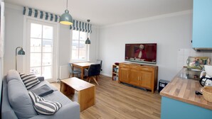Een moderne woonkamer met een bank, eettafel en televisie.