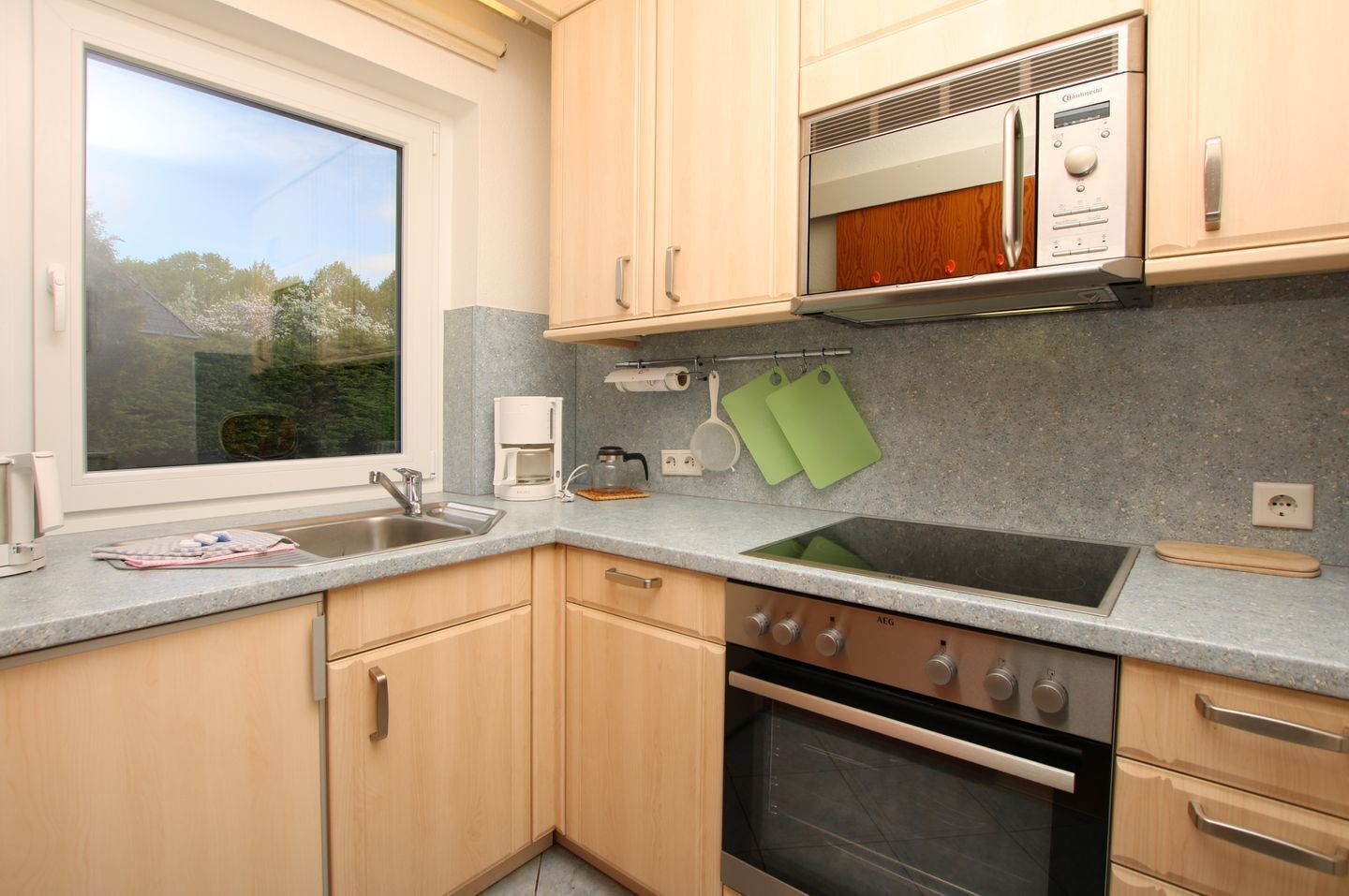 A kitchen with a window, a coffee maker, a sink, and a stove.