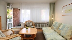En hyggelig stue med en sofa, et spisebord og en fletstol.