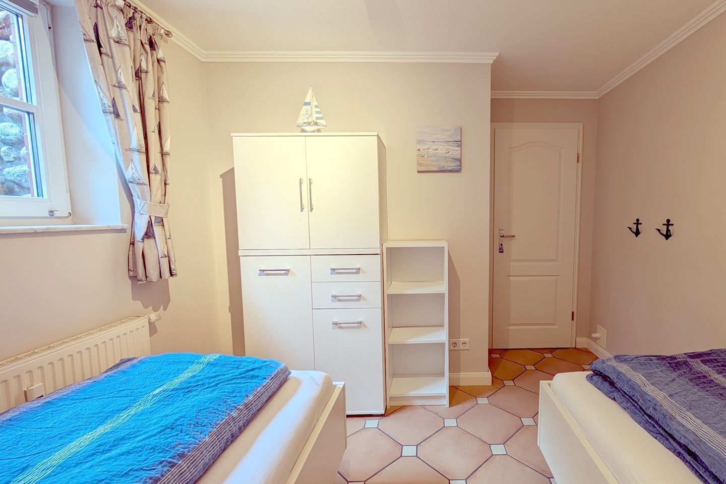 A bedroom with two beds, a wardrobe, a radiator, and a tiled floor.