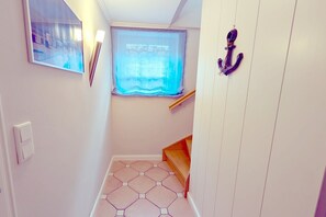 A narrow hallway with a window, a wall-mounted light fixture, a door with a handle, and a wooden shelf. - Stockmannsweg 11b, Apt. 1 - 4-room vacation apartment, approximately 118 m², on the first floor, with (Wyk auf Föhr)