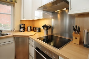A modern kitchen with stainless steel appliances, wooden countertops, and a built-in oven.