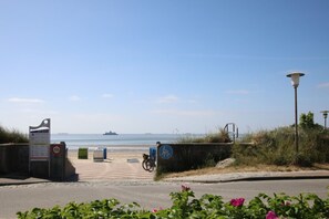 A beach entrance with a signboard, a bicycle, and a lamp post.