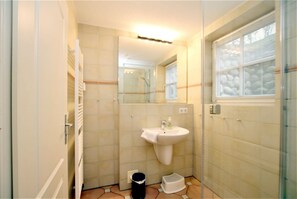 A small bathroom with a sink, mirror, and window.
