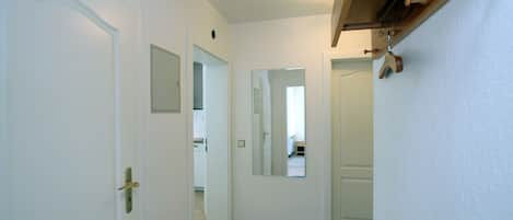 Ein Flur mit weißen Türen, einem Spiegel und einem Holzbalken an der Decke.
