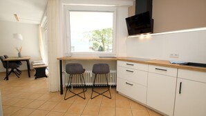 A compact kitchen with a window, two chairs, a dining table, and a TV. - Osterstraße 1, Whg. 2, Haus Flora - Apartment in Wyk/ Südstrand with approx. 60m² (Wyk auf Föhr)