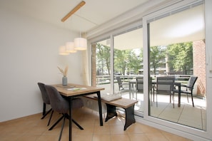 Uma área de refeições moderna com mesa de madeira, cadeiras e luminárias pendentes.