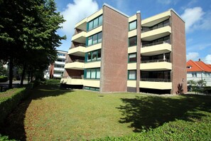 Um edifício de vários andares com varandas, fachada de tijolos e um pátio gramado.
