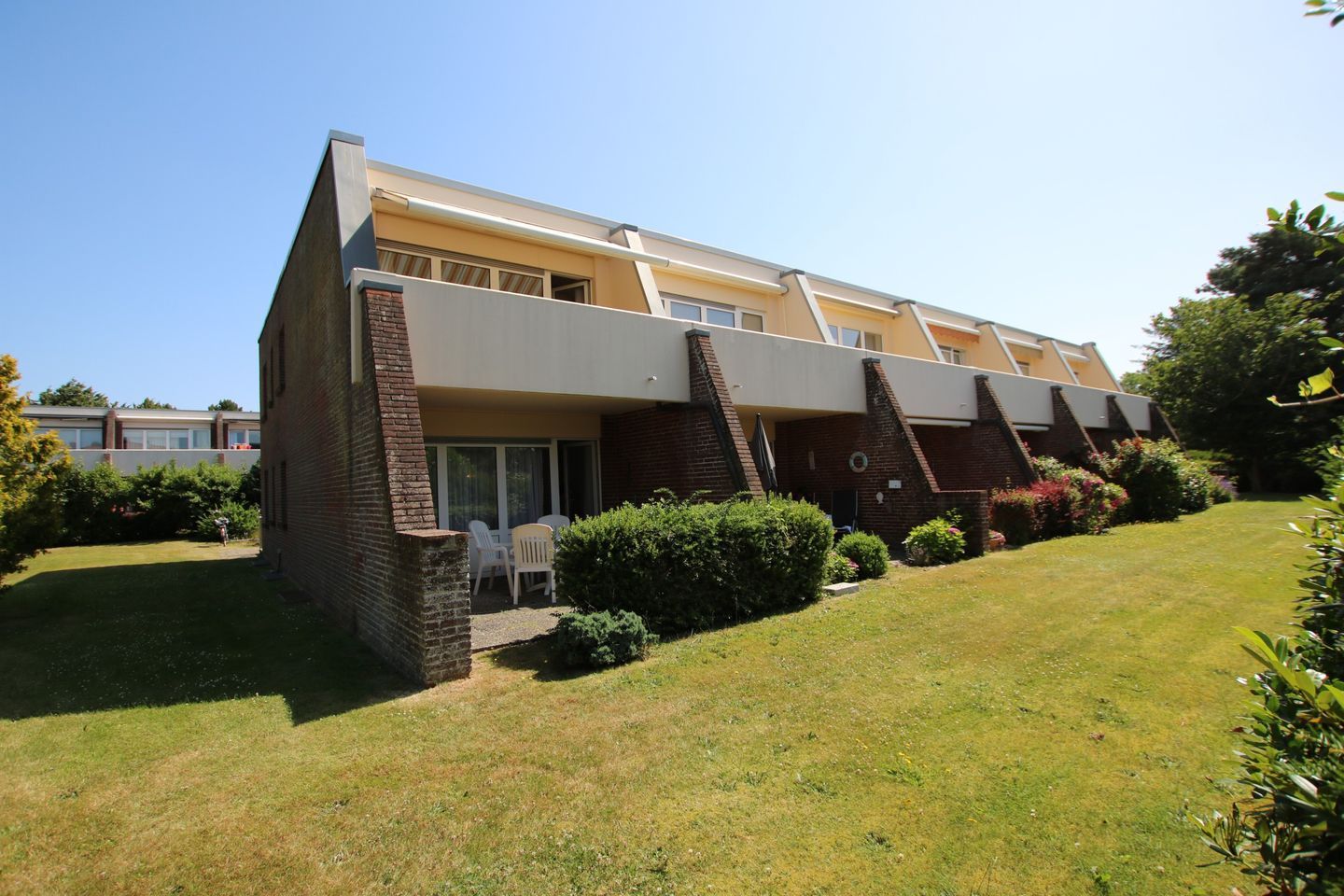 A two-story building with a flat roof, a brick facade, and a small patio area with outdoor seating.