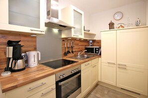 Una cocina moderna con encimera de madera, electrodomésticos de acero inoxidable y muebles en color beige.