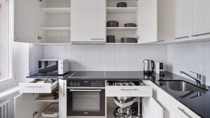 Une cuisine moderne avec des meubles blancs, un four à micro-ondes Bosch, un four Siemens et un évier avec une bouilloire.