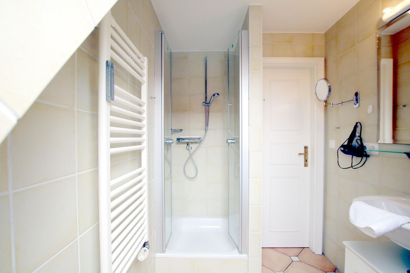 A shower with a glass door, a white bathtub, and a white sink with a mirror above it.