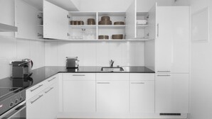 A modern kitchen with white cabinetry, a black countertop, and a built-in oven.