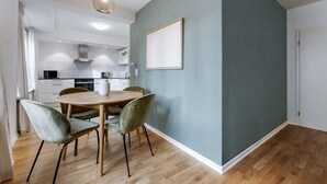 A modern kitchen with white cabinets, a microwave, and a stove. There is a dining area with a round table and four chairs.
