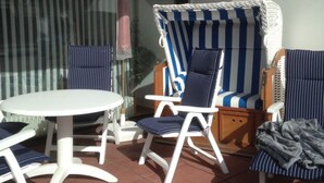 Une terrasse avec une table ronde et deux chaises longues à rayures.