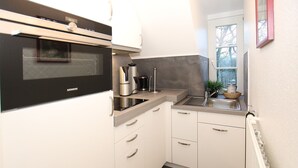 Eine kompakte Küche mit Mikrowelle, Kaffeemaschine und einem kleinen Spülbecken.