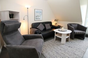 Un salon moderne avec un canapé, un fauteuil et une petite table ronde.