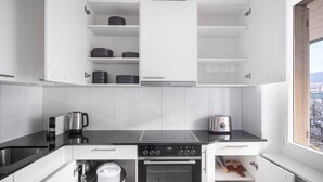 Una cocina moderna con armarios blancos, una encimera negra, un horno Bosch y vistas de la ciudad a través de un ventanal.