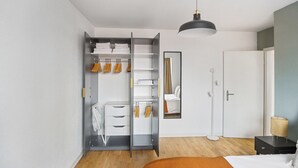 Un dormitorio con armario, espejo, mesita de noche y cama.