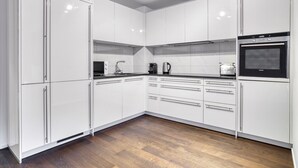 Een moderne keuken met witte kasten, een inbouwoven en een magnetron.