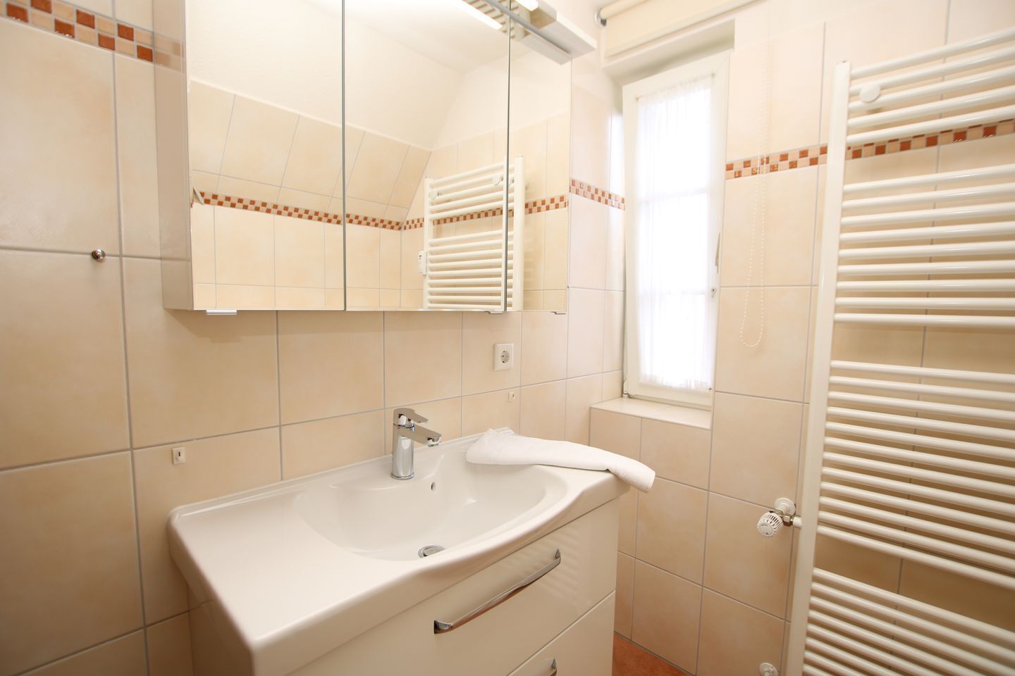 A bathroom with a sink, mirror, towel rack, and a window with blinds.