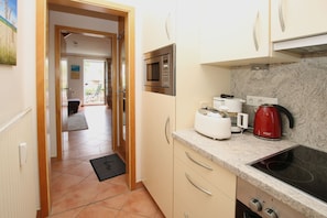 A kitchen with a microwave, toaster, kettle, and stove.