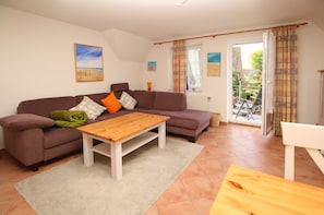 A living room with a sofa, a wooden coffee table, and a view of the outside.