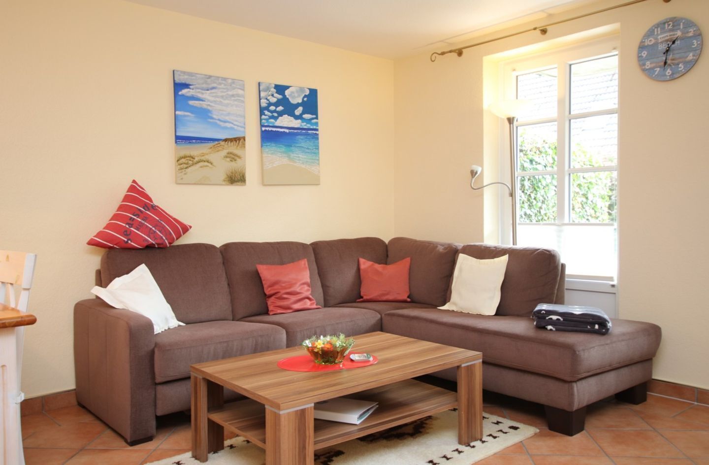 A living room with a brown sofa, a wooden coffee table, and two paintings on the wall.