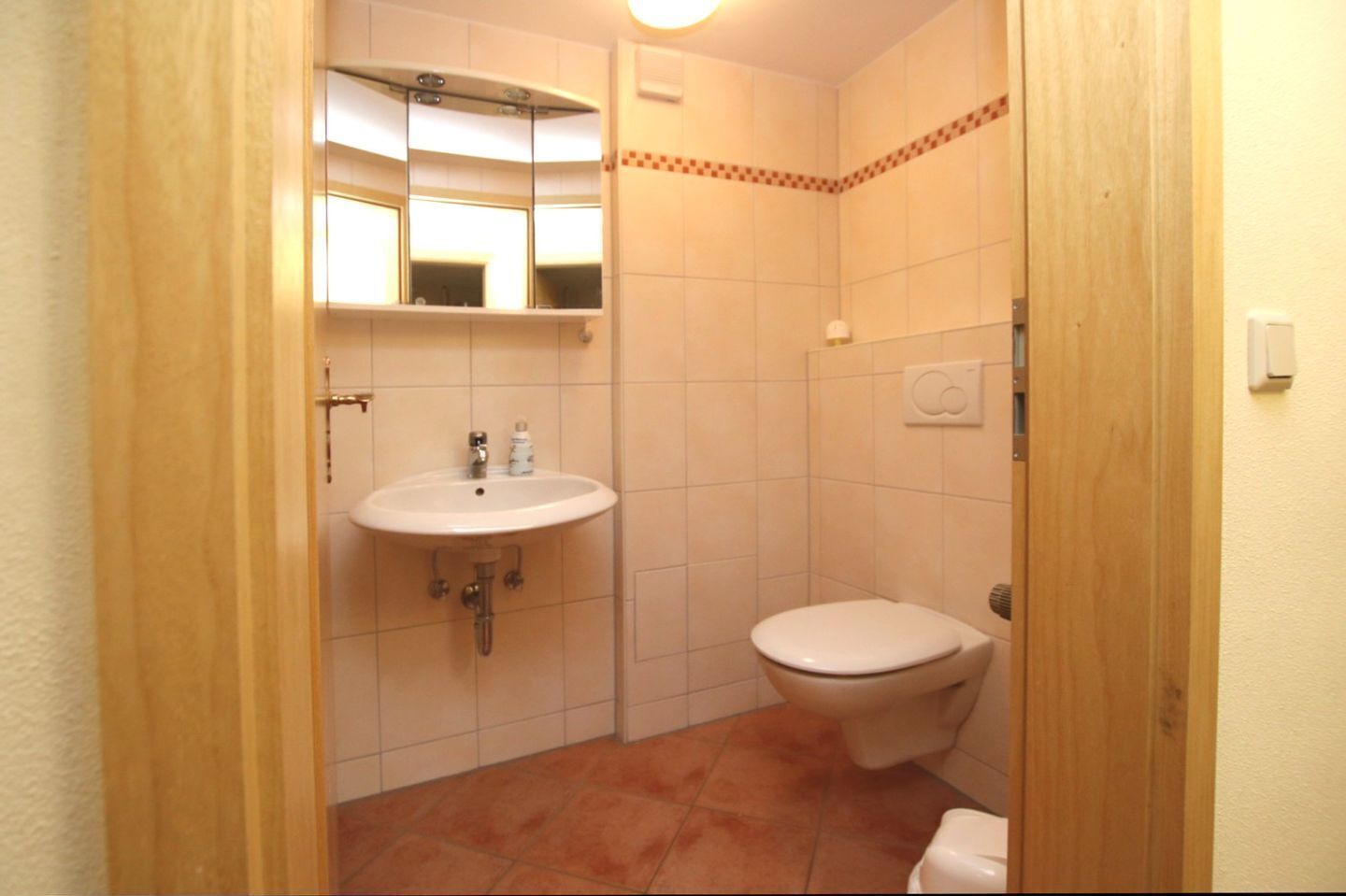 Ein kleines Badezimmer mit Waschbecken, Spiegel und Toilette.