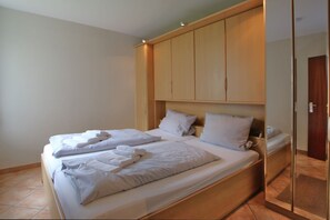 Una habitación de hotel con una cama, cabecera de madera y un espejo.