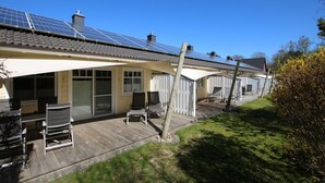 Una hilera de cabañas con paneles solares, un porche cubierto y una terraza de madera.