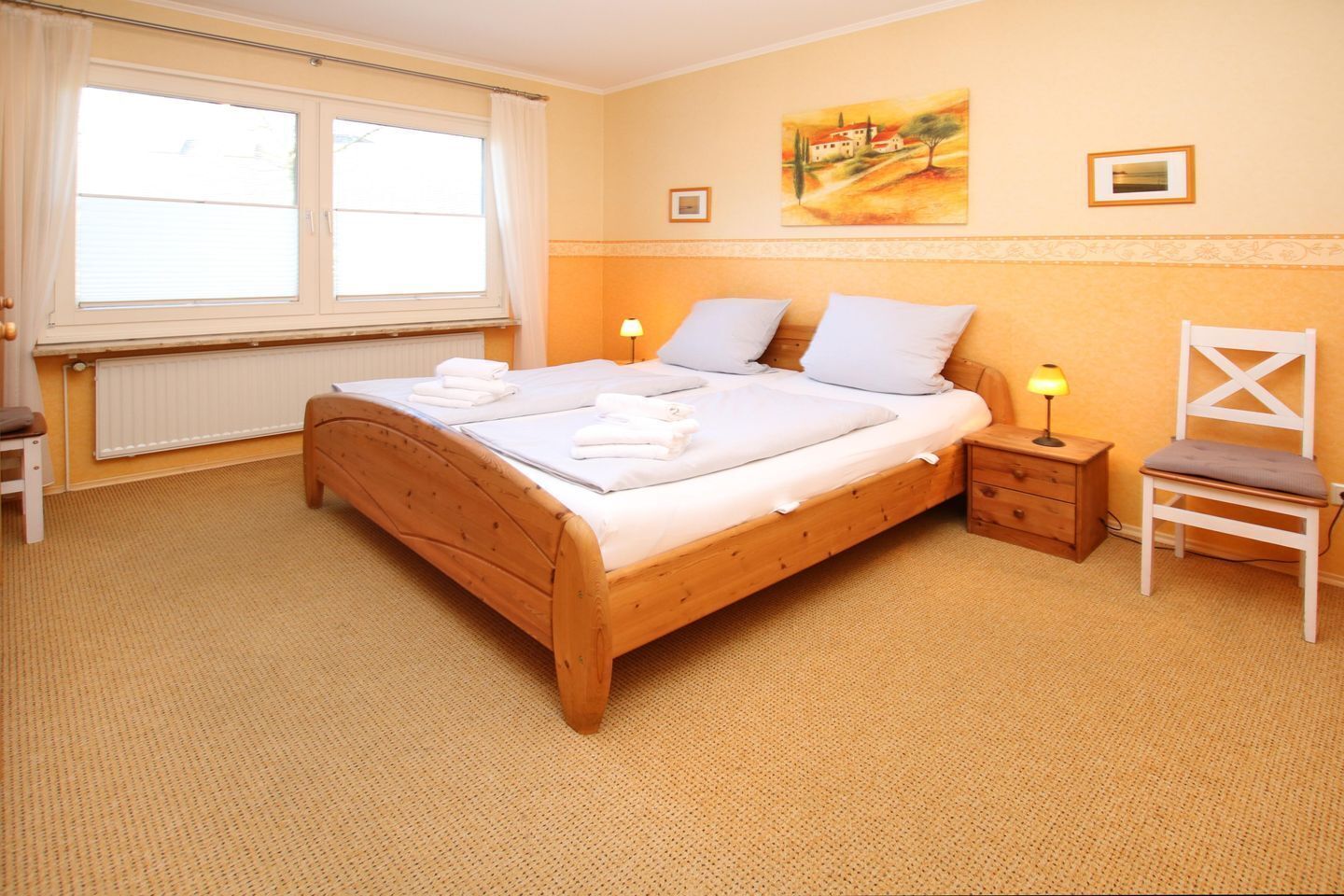 Una camera accogliente con un letto di legno, un comodino, una sedia e una finestra con tende.