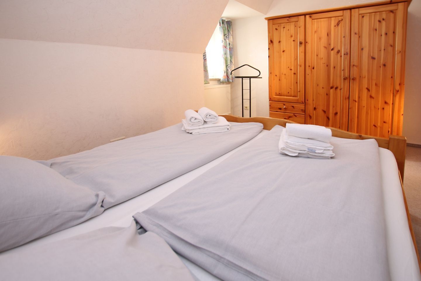 Une chambre d’hôtel avec deux lits, une armoire en bois et un radiateur.