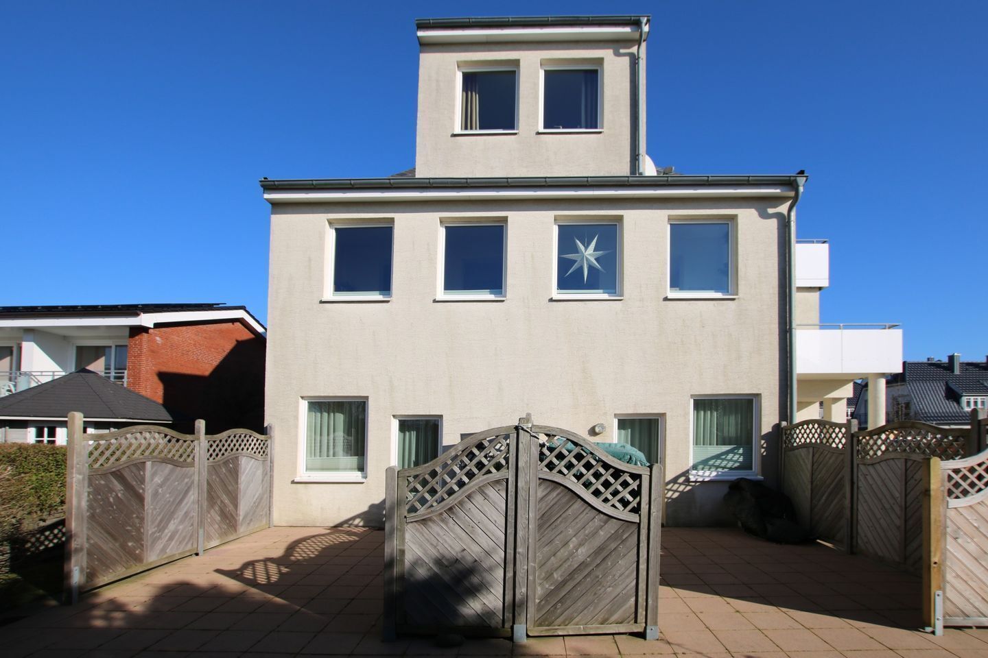Ein zweistöckiges Gebäude mit flachem Dach und zahlreichen Fenstern, darunter ein sternförmiges Fenster im zweiten Stock.