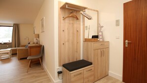 A room with a wooden bench, a desk, a chair, a hanging coat rack, and a wardrobe. - Badestraße 80, Whg. 1, Goting Hus - Newly renovated apartment on the mezzanine floor, (Wyk auf Föhr)