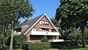 A two-story house with a sloped roof, a balcony, and a well-maintained garden. - Badestraße 80, Whg. 1, Goting Hus - Newly renovated apartment on the mezzanine floor, (Wyk auf Föhr)