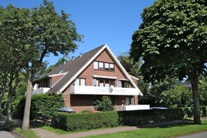 Ein zweistöckiges Haus mit geneigtem Dach, einem Balkon und einem gepflegten Garten.