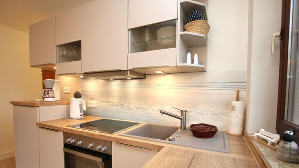 A modern kitchen with a built-in oven, a stainless steel sink, and a coffee maker on the countertop. - Badestraße 80, Whg. 1, Goting Hus - Newly renovated apartment on the mezzanine floor, (Wyk auf Föhr)