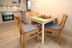 Une cuisine moderne avec des chaises en bois, une table et un four encastré.