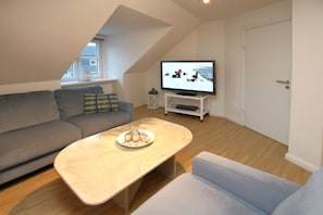 A modern living room with a sofa, a coffee table, and a television. - Mittelstraße 18, Whg. 1, Haus am Rosenbeet - Holiday apartment with 3 rooms on (Wyk auf Föhr)