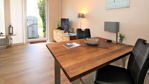 Una sala de estar moderna con una mesa de comedor de madera, un televisor y una lámpara.