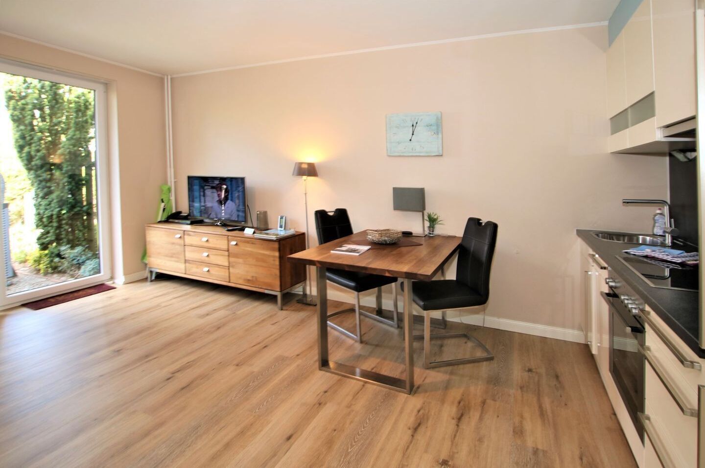 Une cuisine moderne dotée d’un four encastré et d’un coin repas avec une table et des chaises en bois.