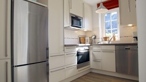 Una cocina moderna con electrodomésticos de acero inoxidable, muebles de cocina blancos y un ventanal con vistas.