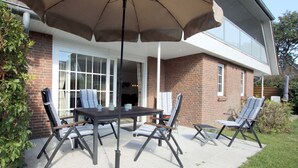 Un patio con mesa y sillas, una sombrilla y un edificio de ladrillo al fondo.