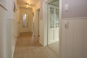 A hallway with white walls, a tiled floor, and a door with frosted glass panels. - Starklef 34a, Whg. 2, Huus Starklef - Komfort Ferienwhg. in Wyk, 4 Personen, OG in 2- Familienhaus, (Wyk auf Föhr)