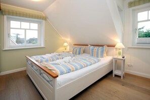 A bedroom with a bed, two bedside tables, a window, and a lamp. - Starklef 34a, Whg. 2, Huus Starklef - Komfort Ferienwhg. in Wyk, 4 Personen, OG in 2- Familienhaus, (Wyk auf Föhr)
